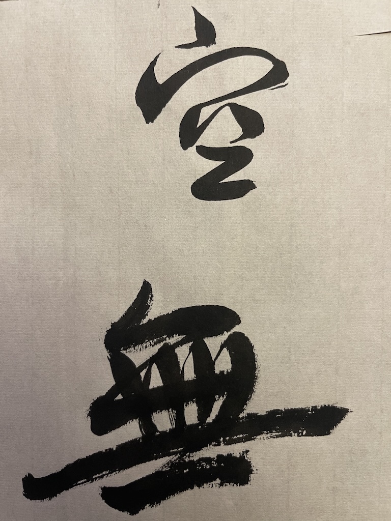 The character 空 (emptiness) on top and 無 (un-, also a synonym for emptiness), key words in the Heart Sutra, on the bottom, in black sumi ink on white rice paper.